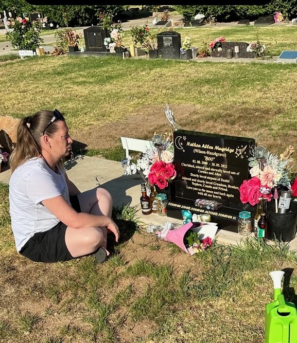 Woman sitting beside gravestone.