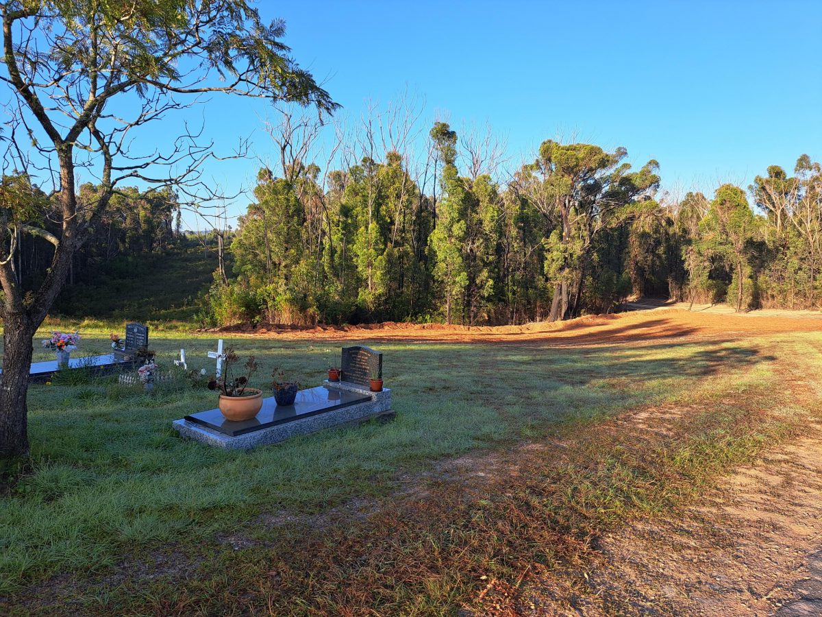 One of the bushfire waste clearing sites - Mogo Cemetery, with graves in the foreground and trees in the background