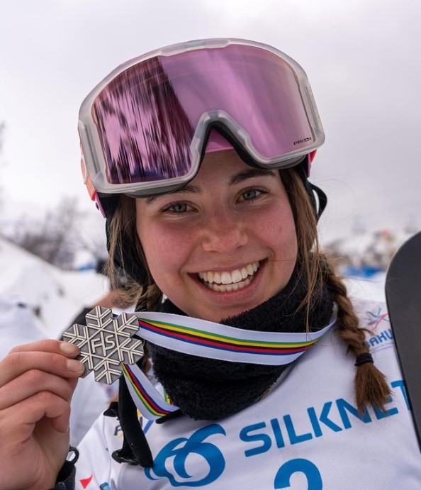 Josie Baff in snowboard gear holding her silver medal 