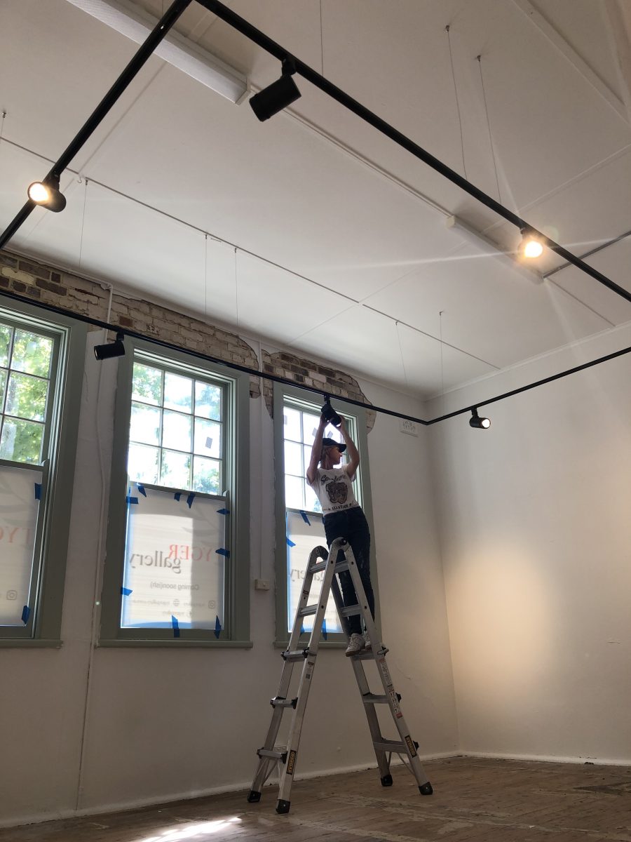 Woman fixing lights in gallery