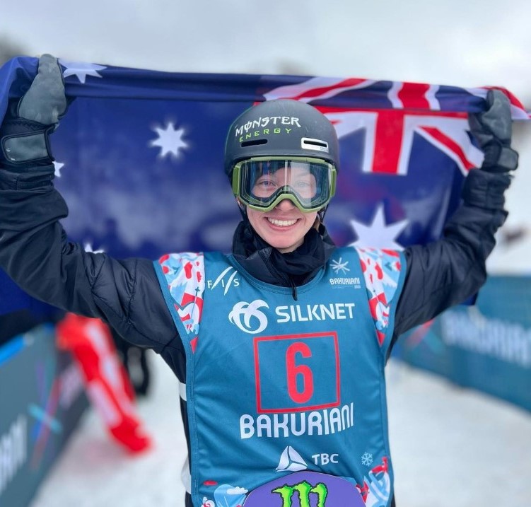 Tess Coady in her snowboard gear holding up the Australian flag 