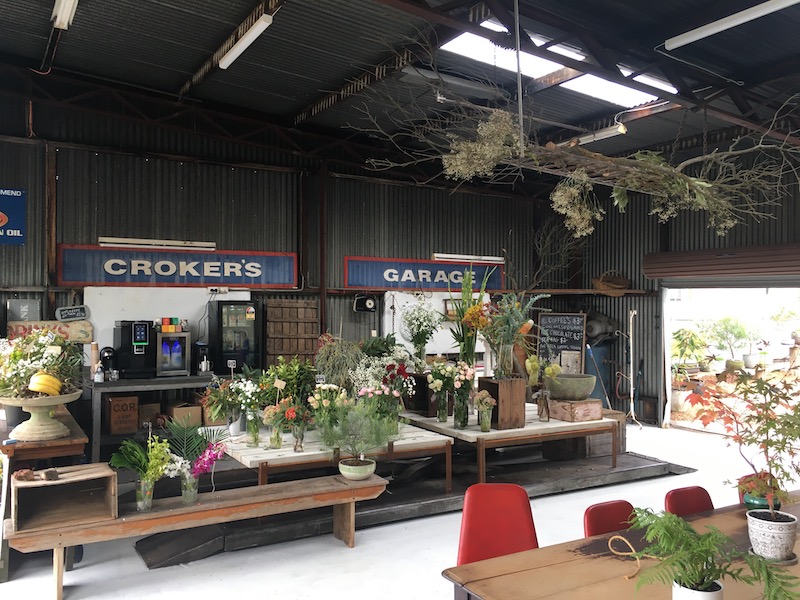 The old Croker's Garage sign, surrounded by plants and flowers from the new nursery