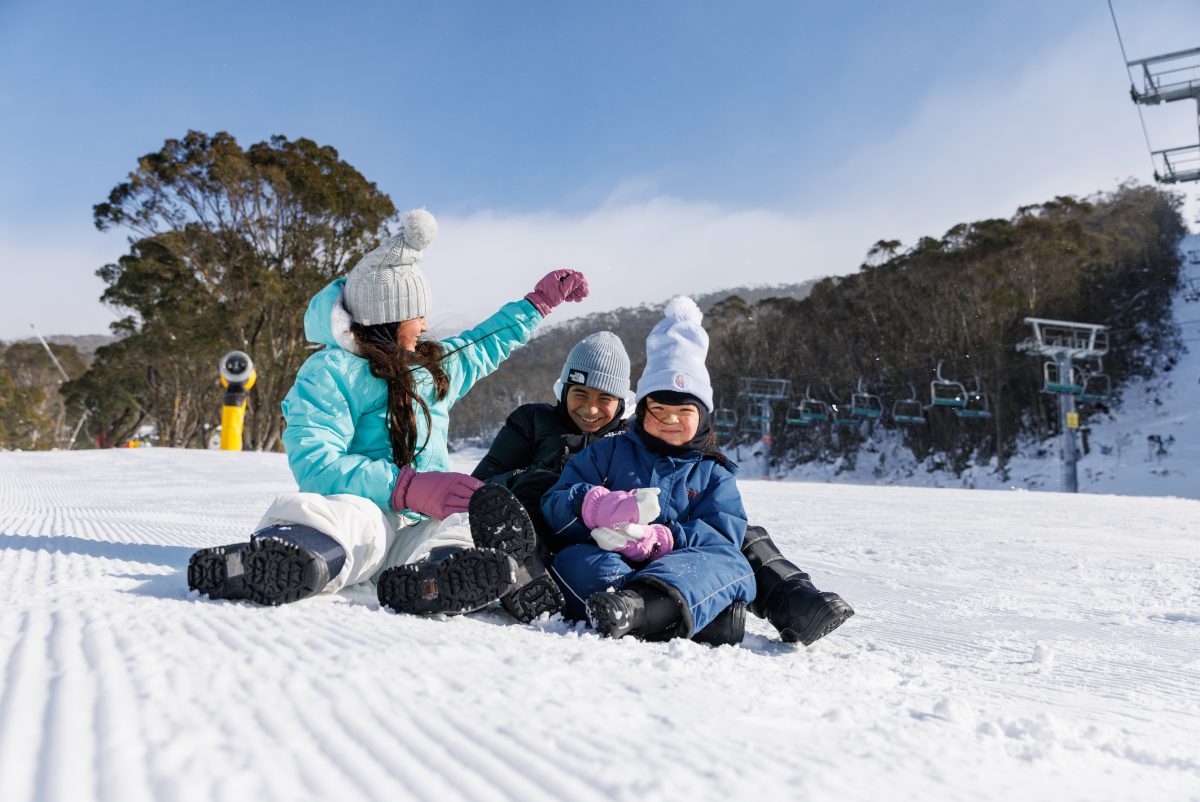 woman and two kids playing in the snow at ski resort