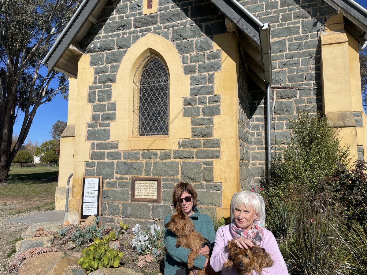 Two women and dogs outside old church