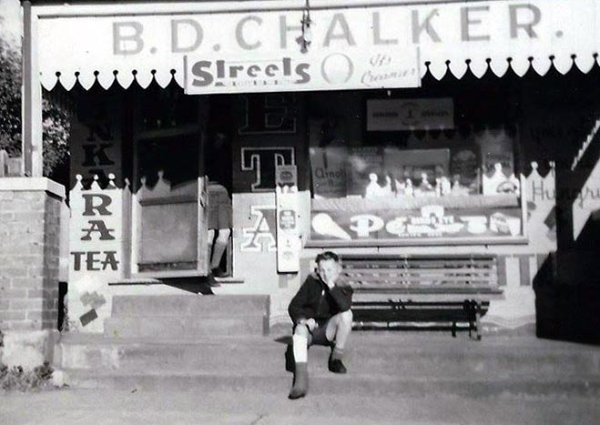 Black-and-white photo of Bruce Muffett sitting on the steps of the Chalkers shop during its heyday.