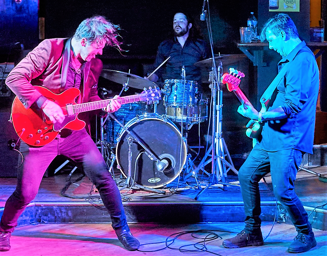 The SunBears in the middle of a performance, with two members playing guitars and one on drums