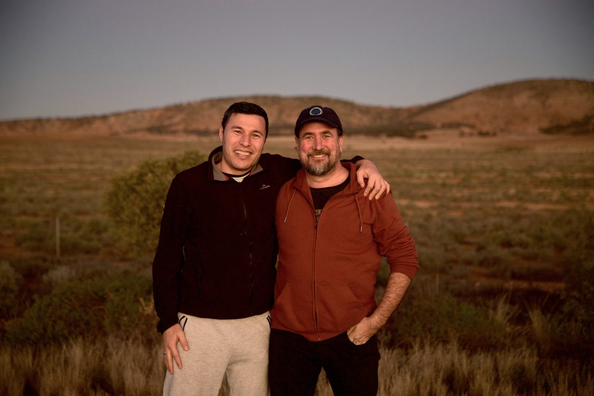two men in front of a sweeping plain at dusk