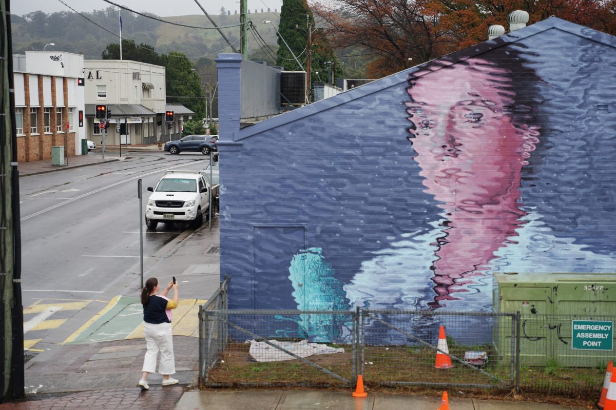 Woman takes photo of mural on building
