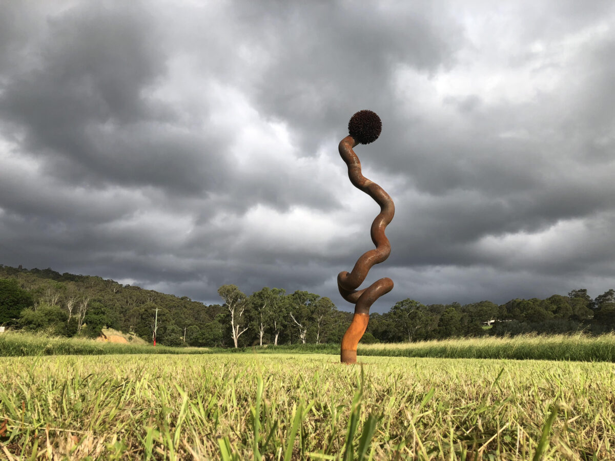 a sculpture in a paddock under a cloudy sky
