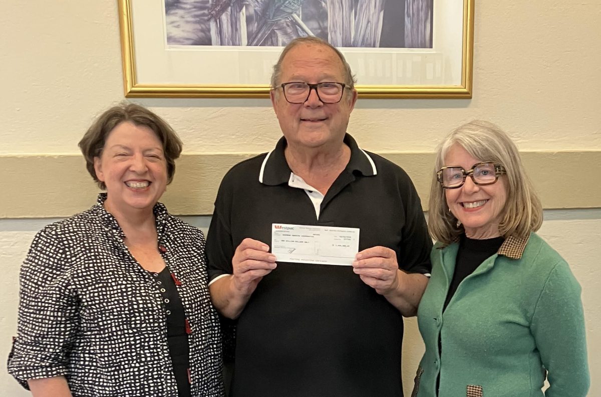 Two women flank man holding cheque 