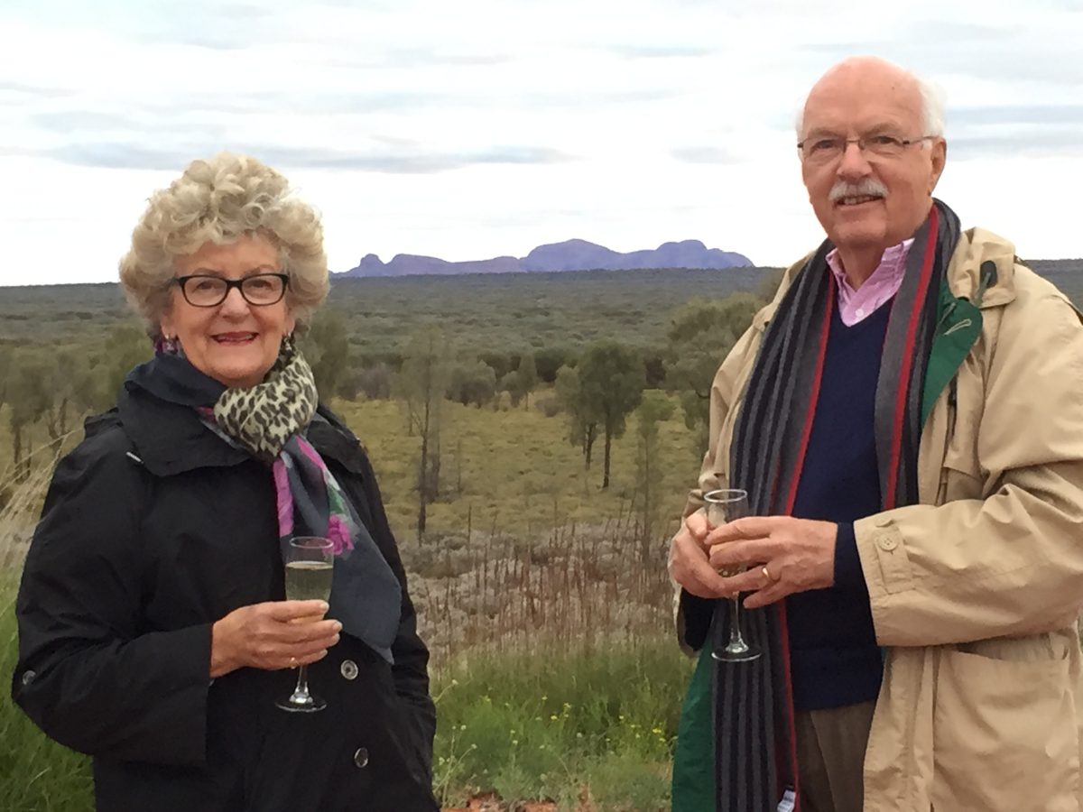 older man and woman in outback with wine glasses