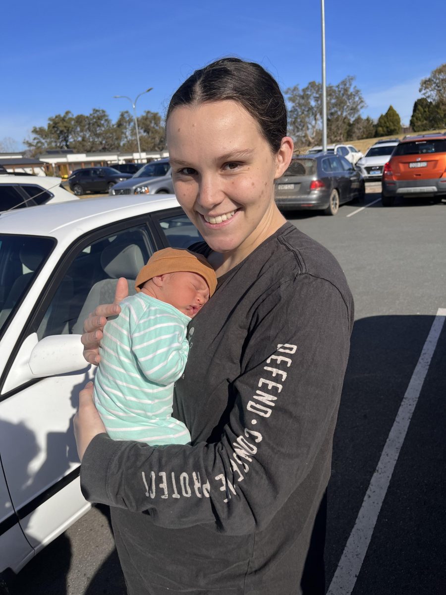 mum holding newborn bub in carpark