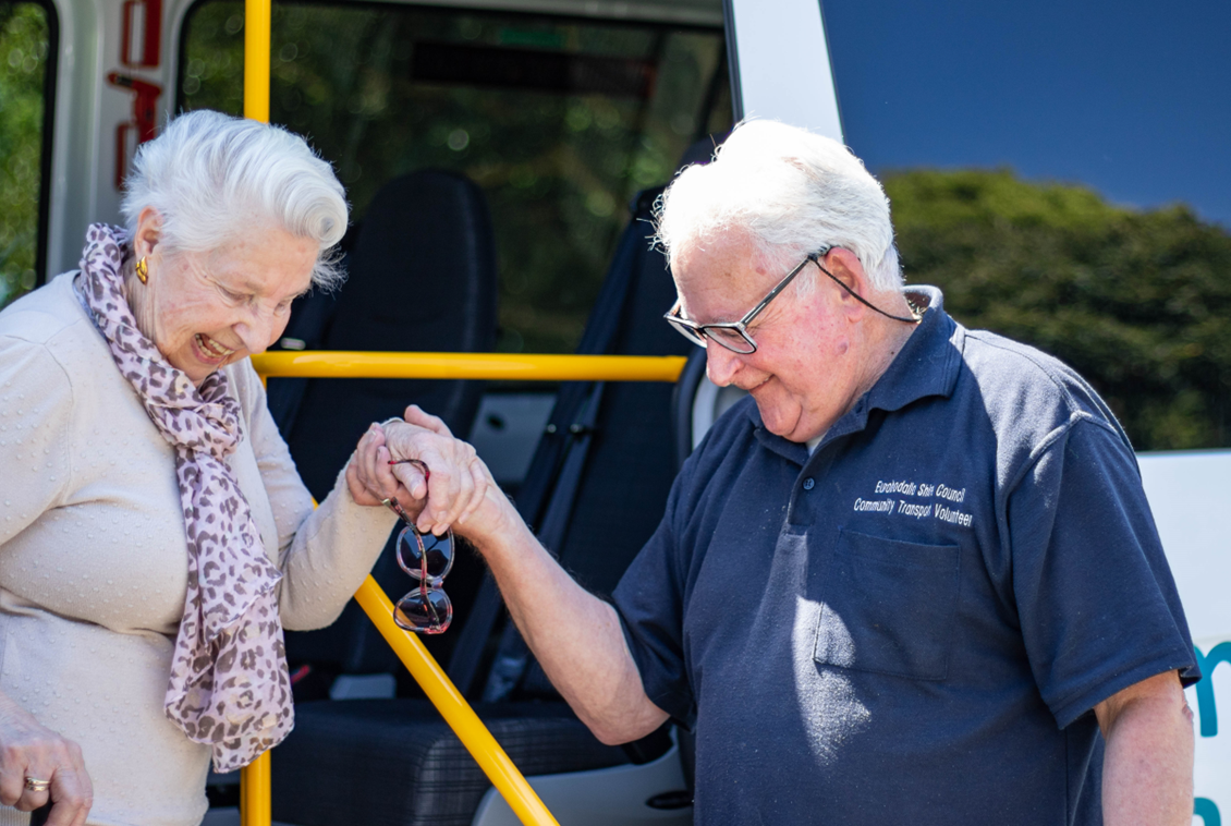 elderly man helping elderly woman alighting from bus