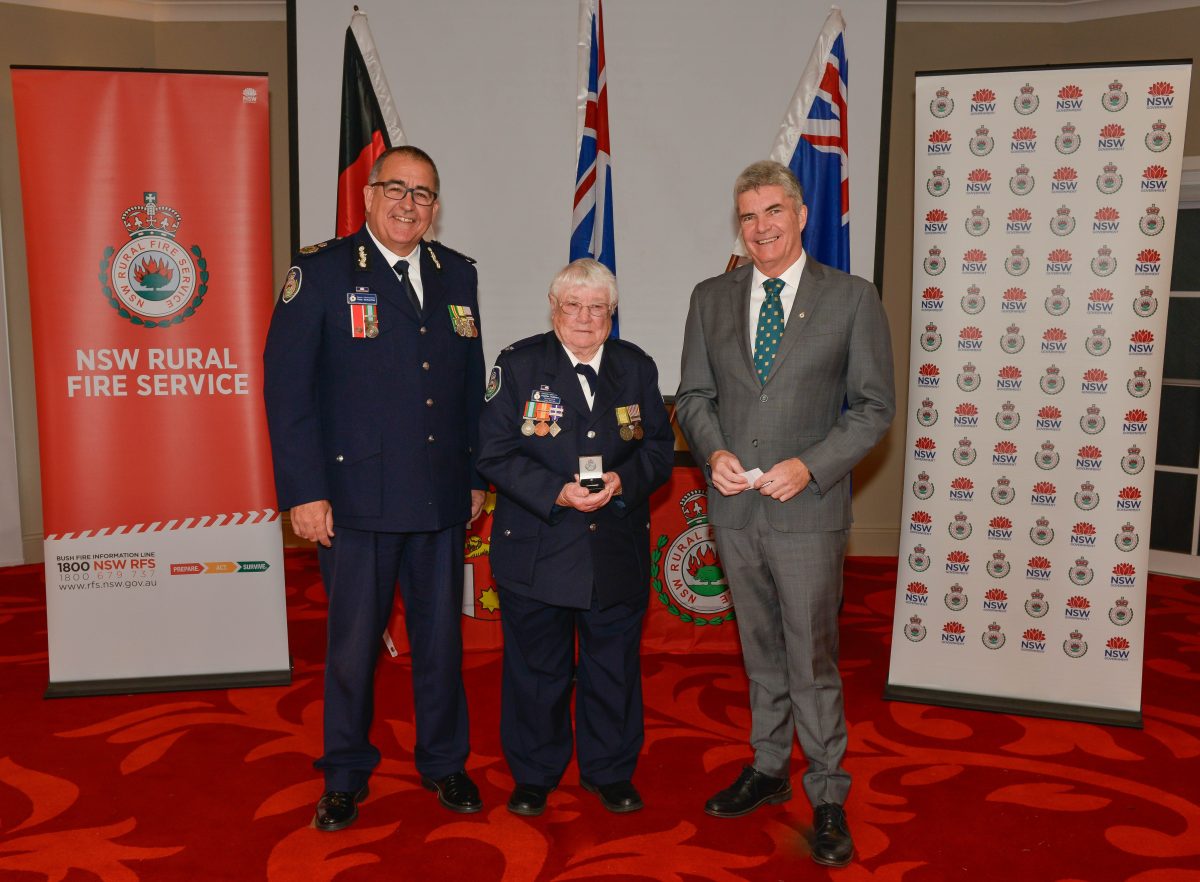 Heather standing with her medal alongside the RFS Deputy Commissioner and Member for Monaro.