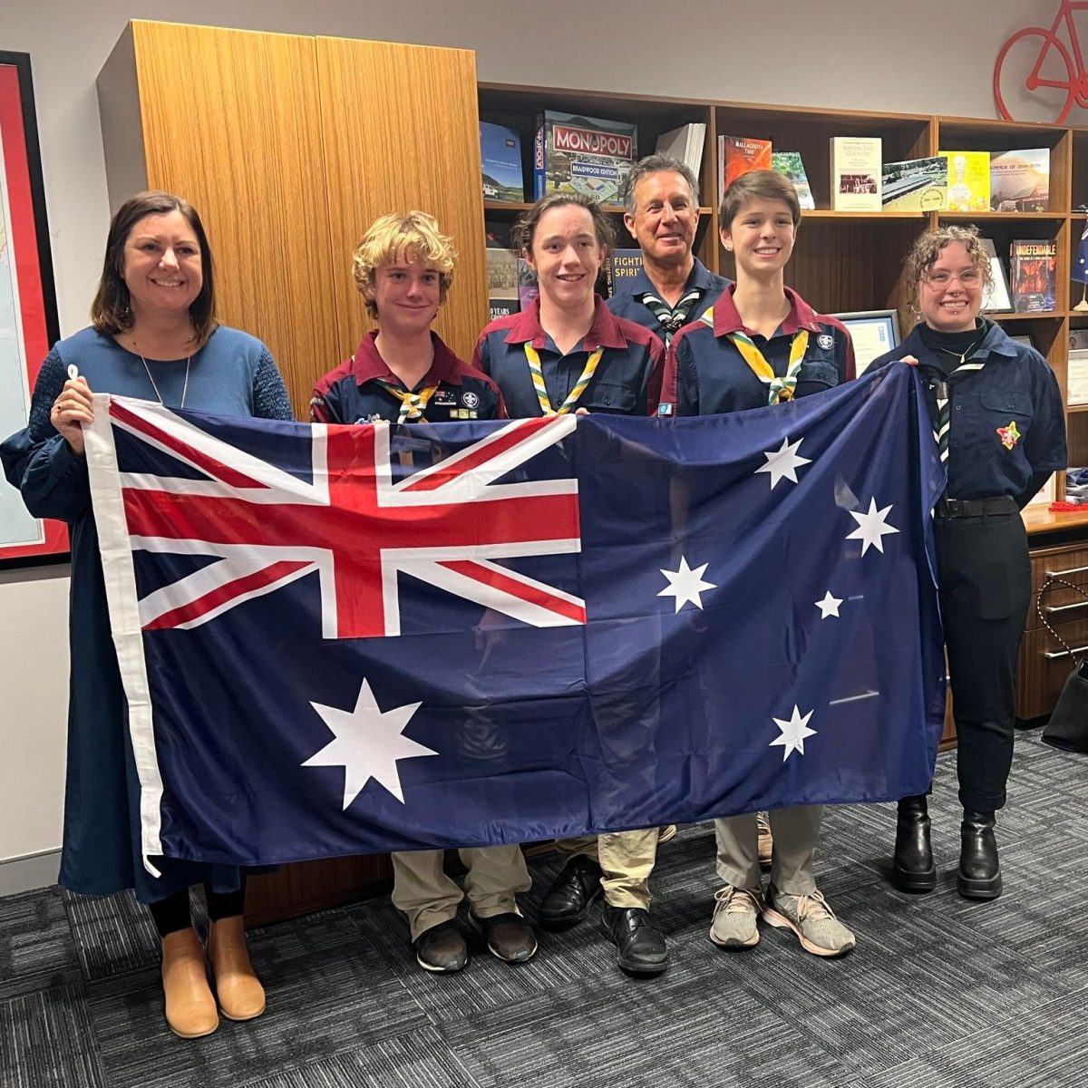 Six people standing in a line holding an Australian flag