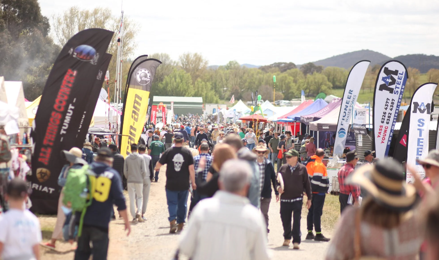 A crowd of people walking in front of market stalls at Murrumbateman Field Days