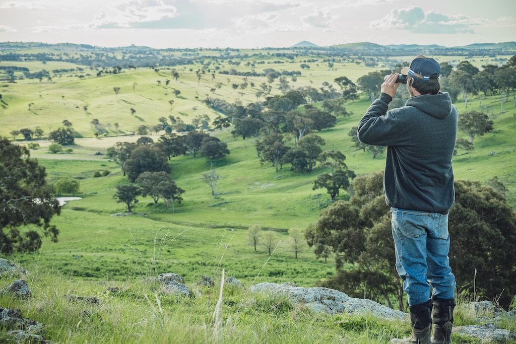 Man with binoculars looking at farmland