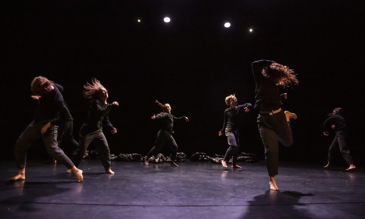 Young people dancing in a loose circle, dressed in black