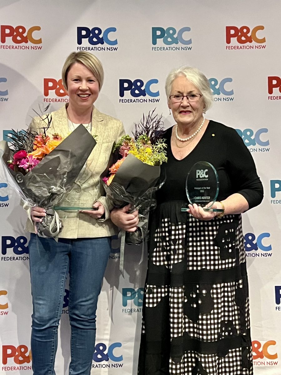Two women hold bouquets of flowers and glass awards