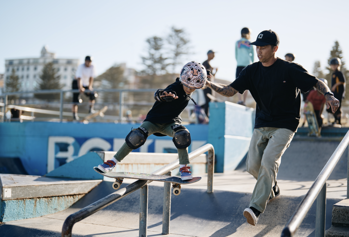 A man helping a child perform a skateboard trick