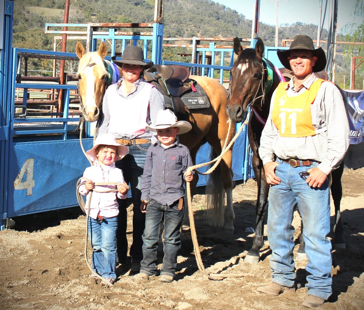 A mum and dad and their two children - a girl and boy - and two stockhorses posing in a horse arena