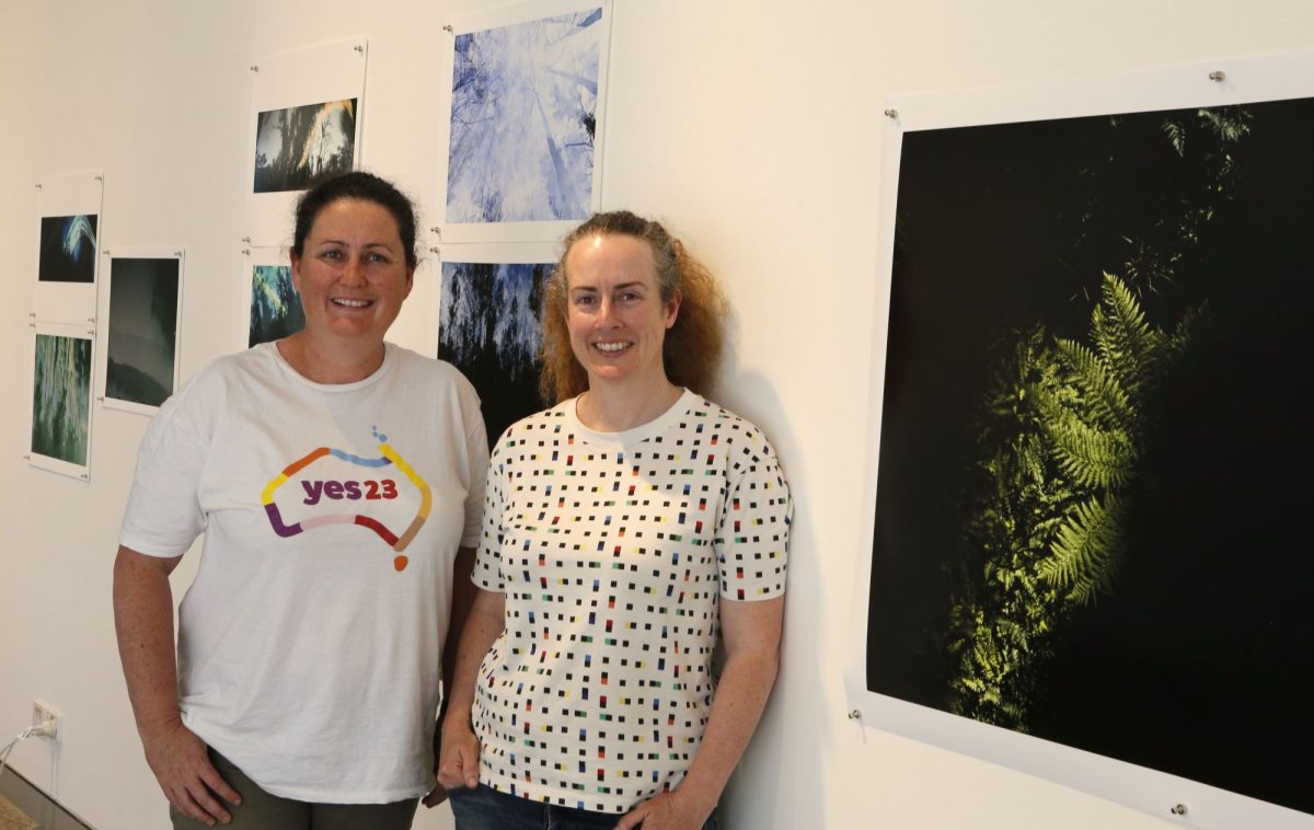 Two women standing in front of a wall of artworks