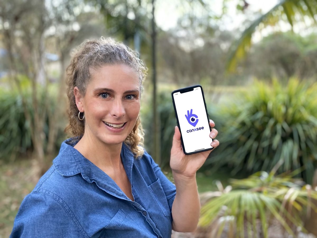 A woman holding a phone with a logo on the screen