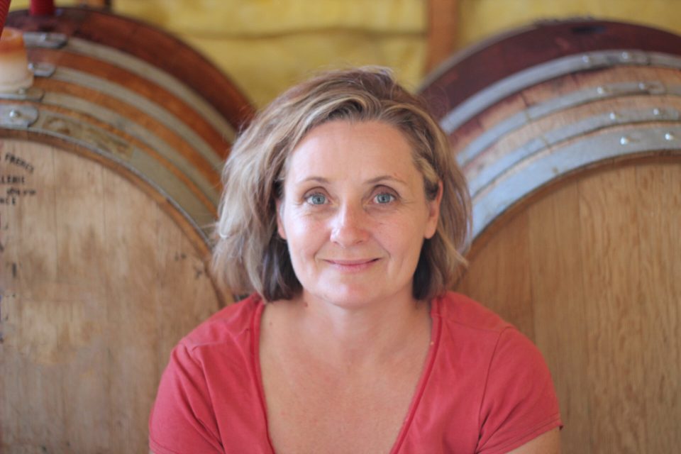 a woman in front of barrels of wine