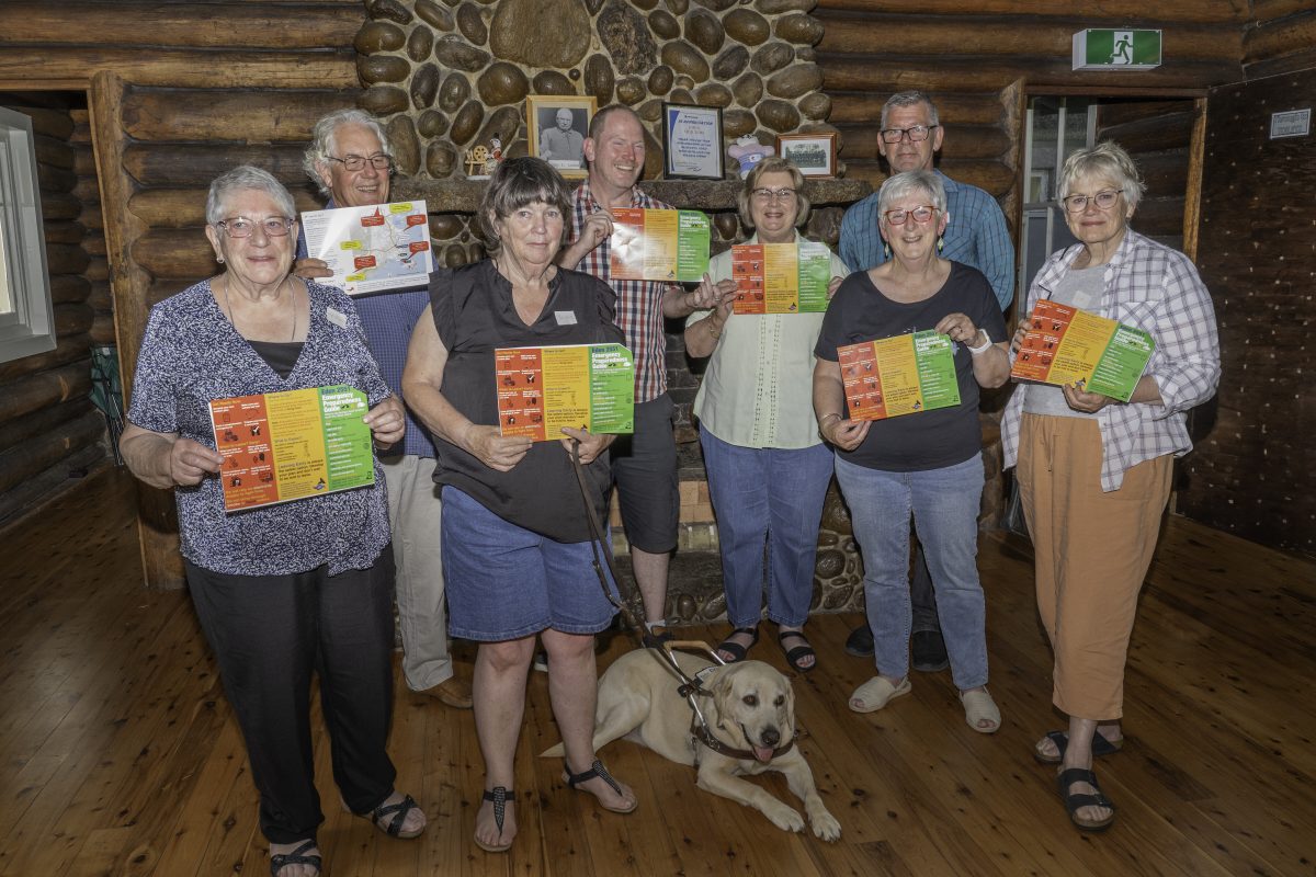 group of people holding brochures, with dog in foreground