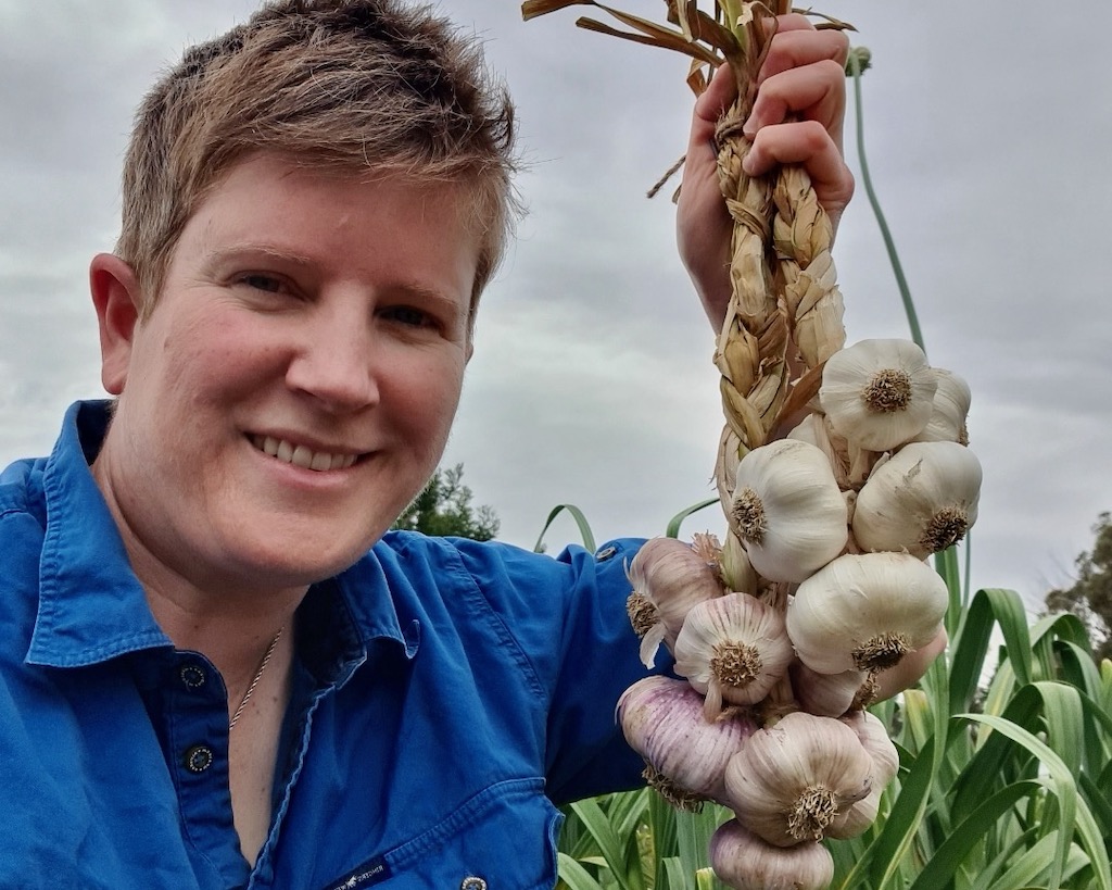 woman holding a bunch of garlic on a farm