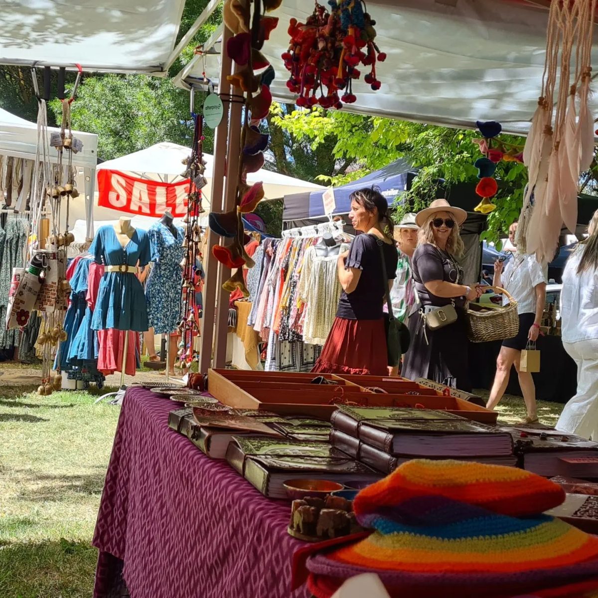 People browsing at outdoor market stalls on a sunny day