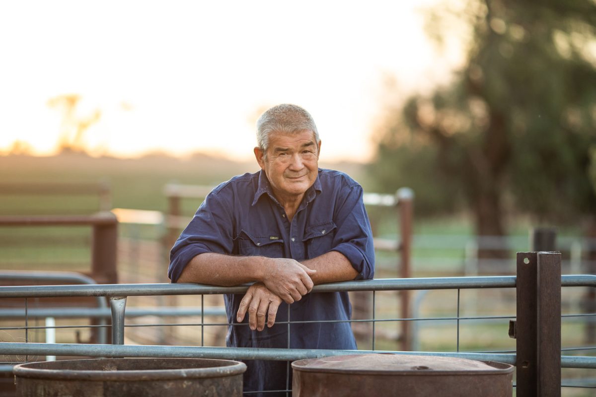 Man leaning on farm fence