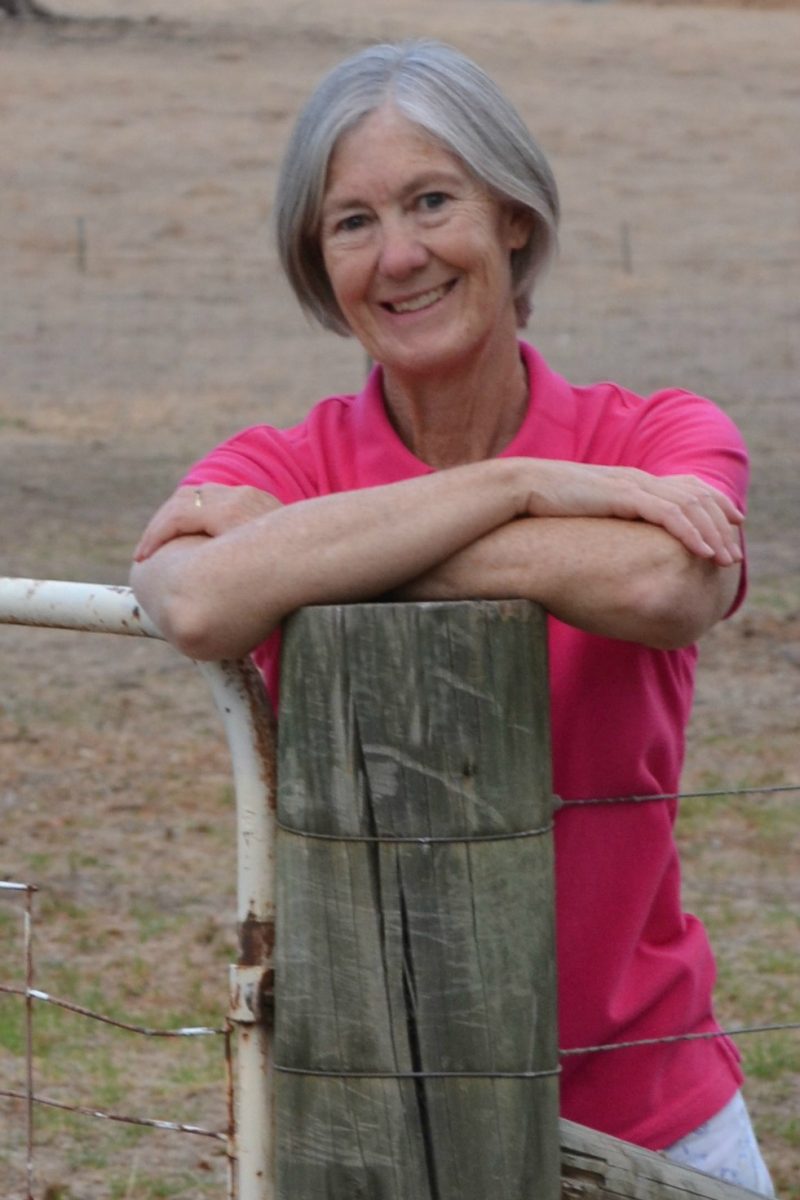 Woman leanin on fencepost in paddock