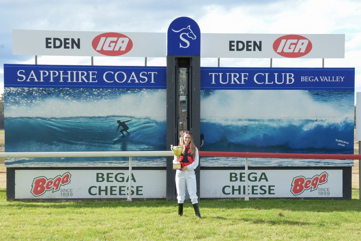 A woman holding a trophy at a racecourse