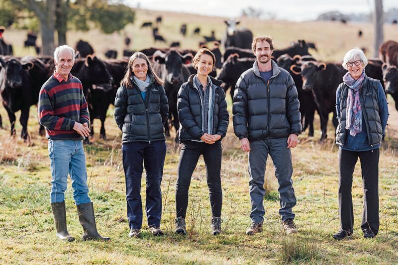 Farming family in front of mob of Angus cattle