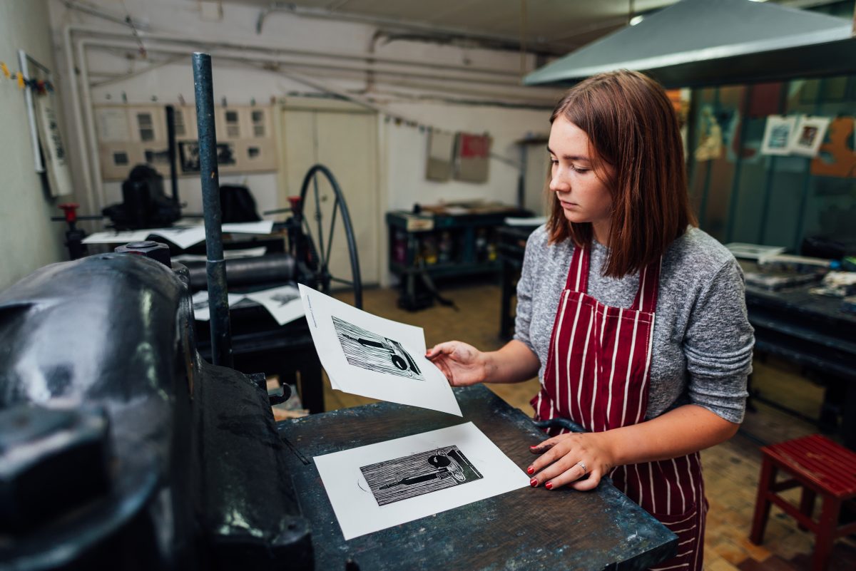 girl prints linocut on the machine.