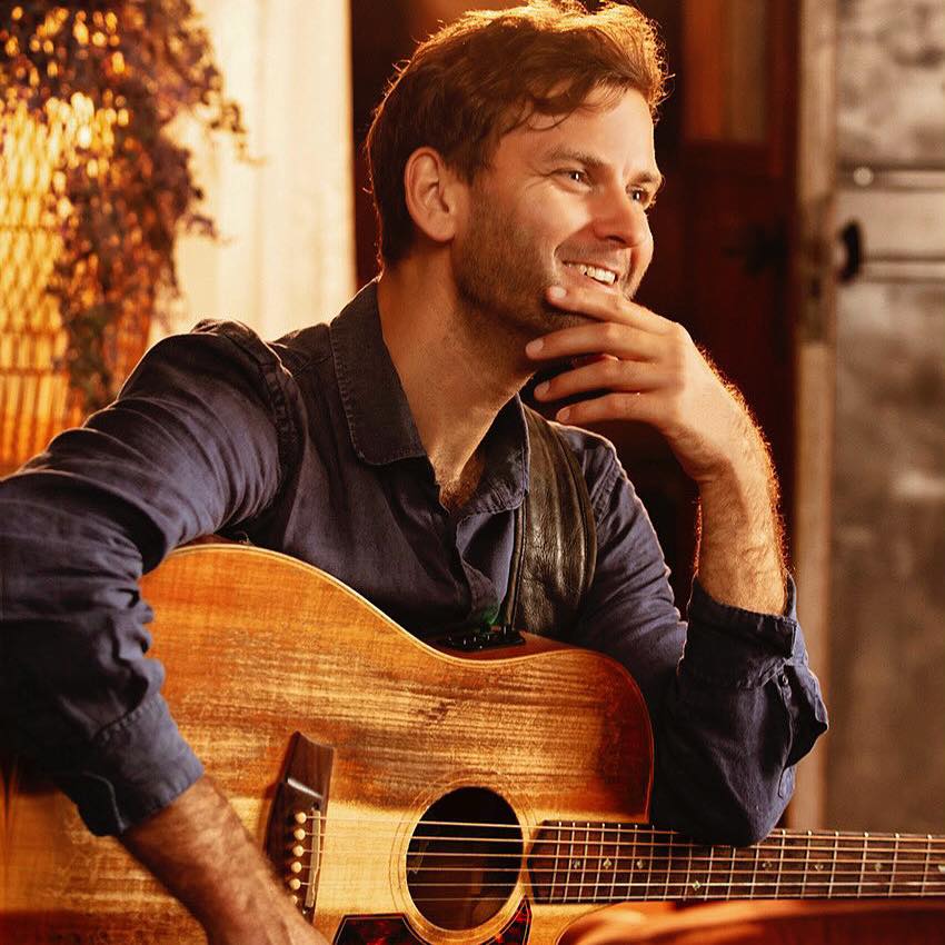 A man holding a guitar and smiling