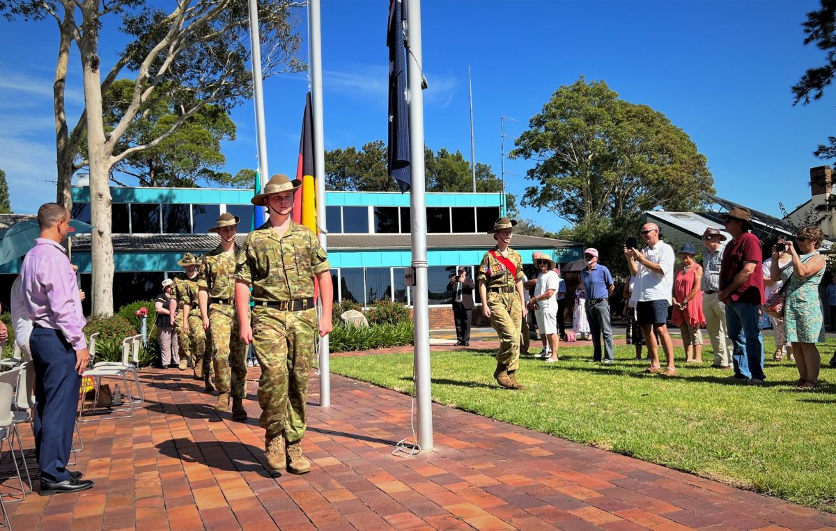 People watching army cadets in uniform during an exercise by flagpoles