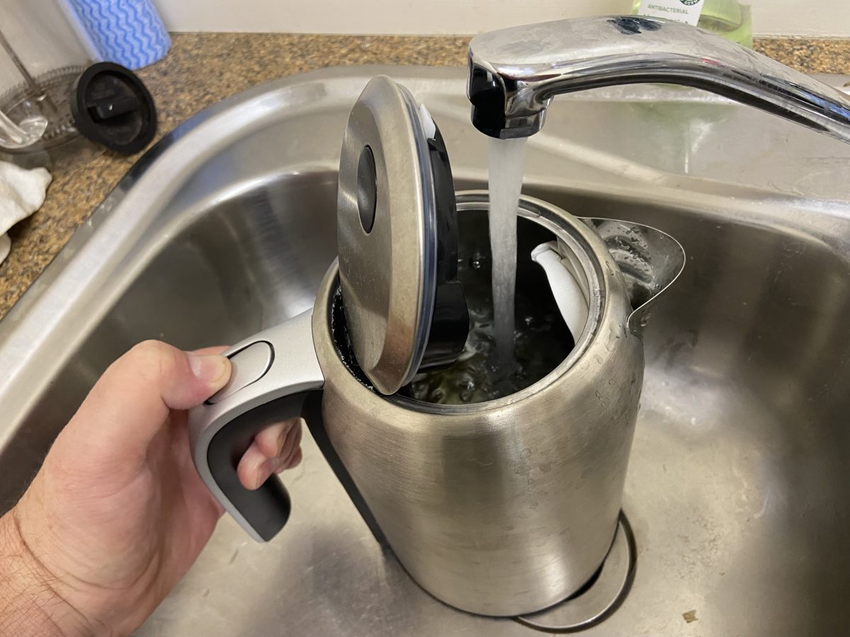 Hand holding a kettle being filled under the tap