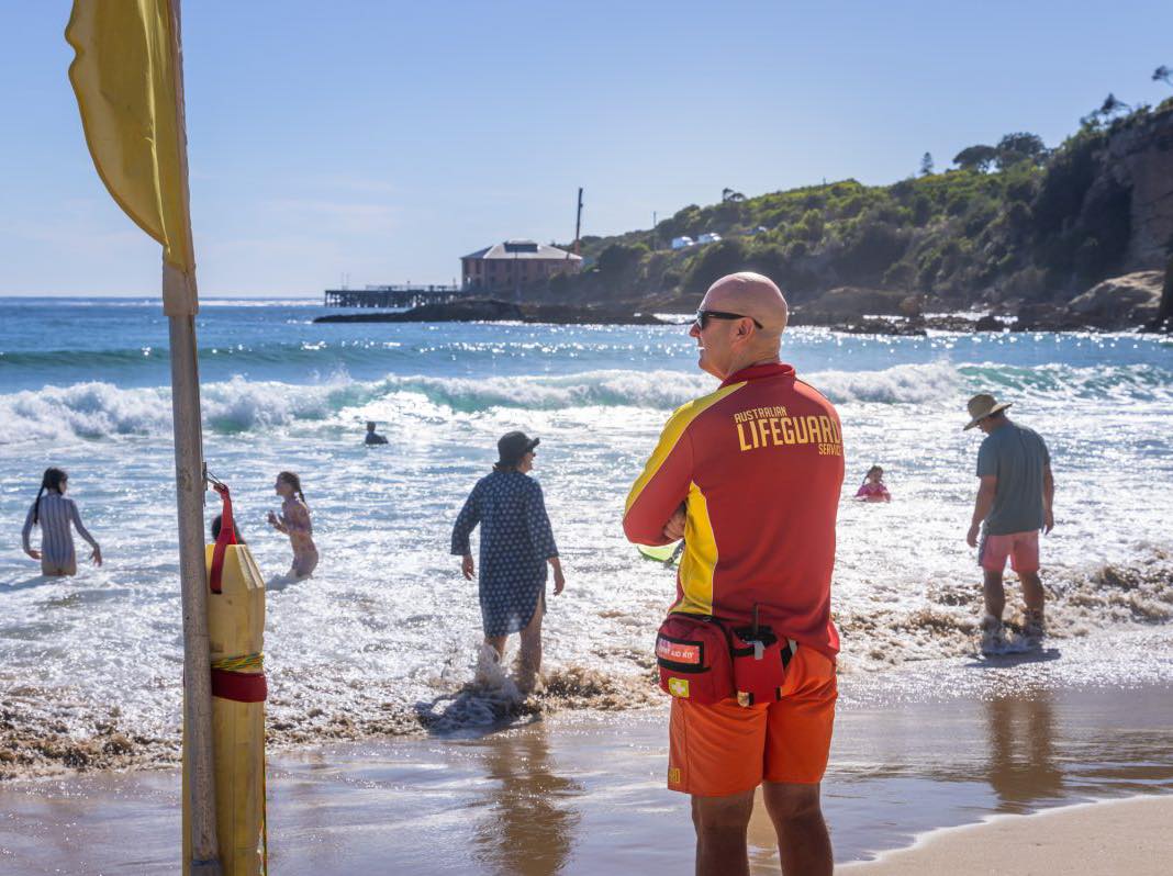 A lifeguard in uniform watching people in the water
