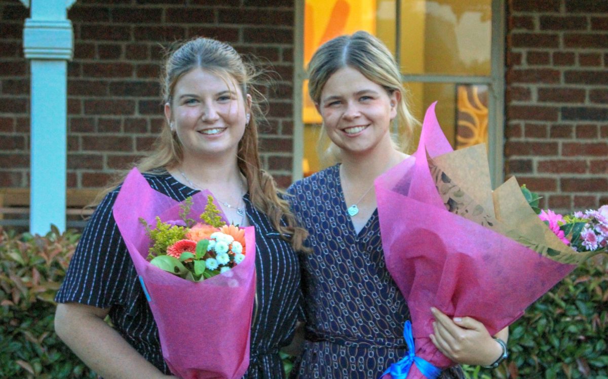 Two smiling young women holding bouquets