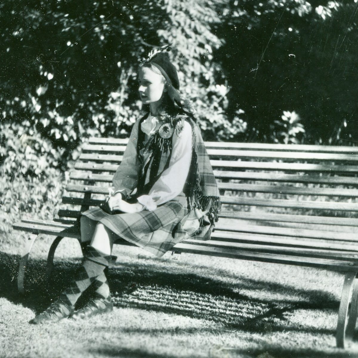 girl dressed in Highland dance gear sitting on a park bench