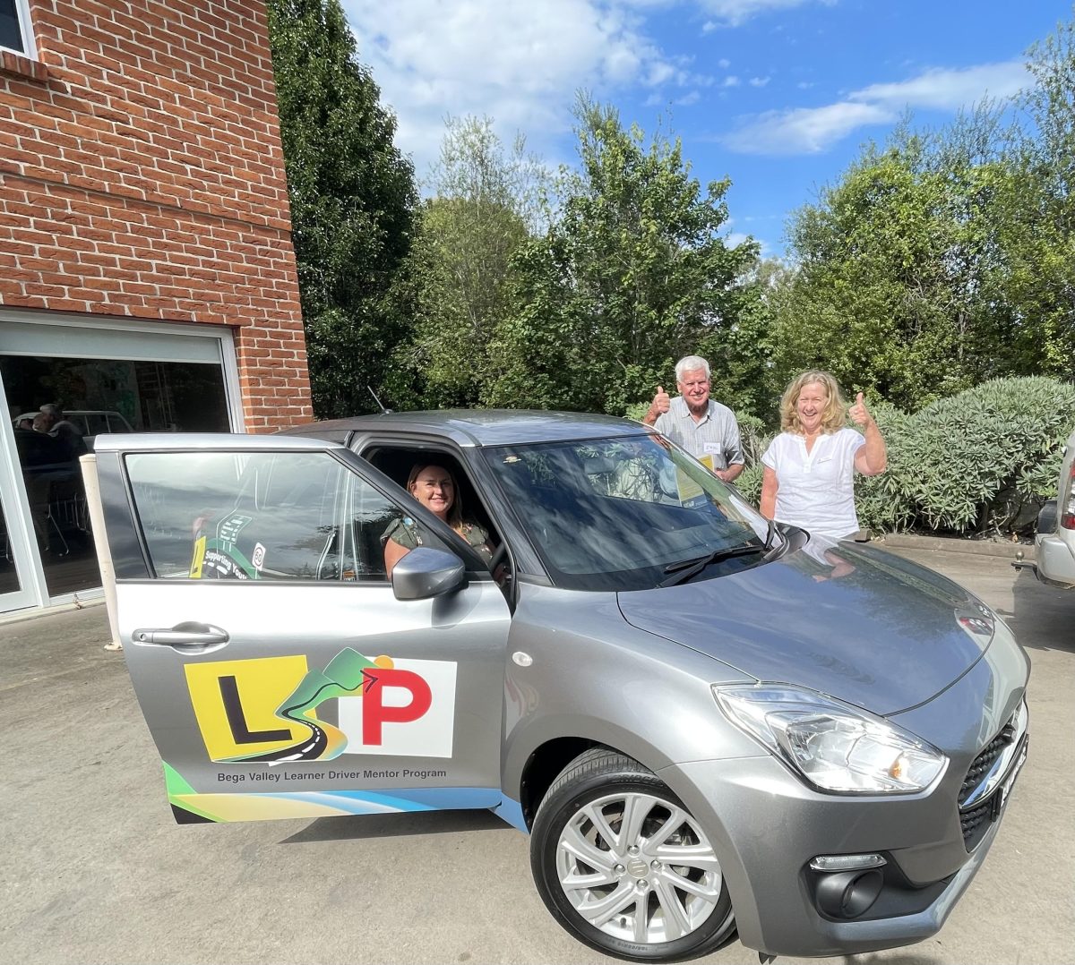 Three people standing around a car