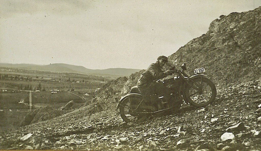 A man riding a motorbike with sidecar up a hill circa 1920s 