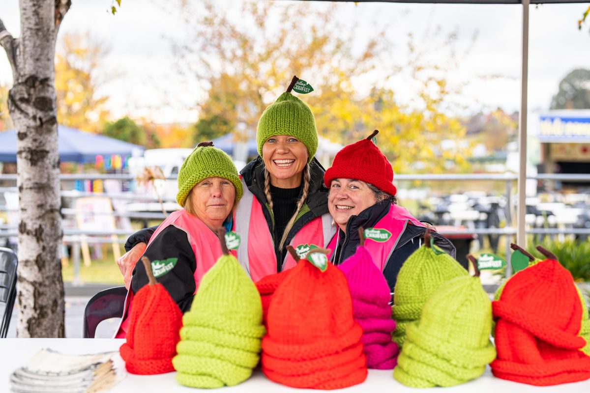 three women standing behind a collection of colourful beanies for Ciderfest