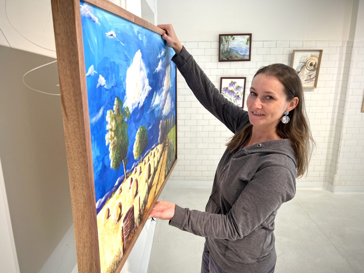 A woman standing in front of her painting