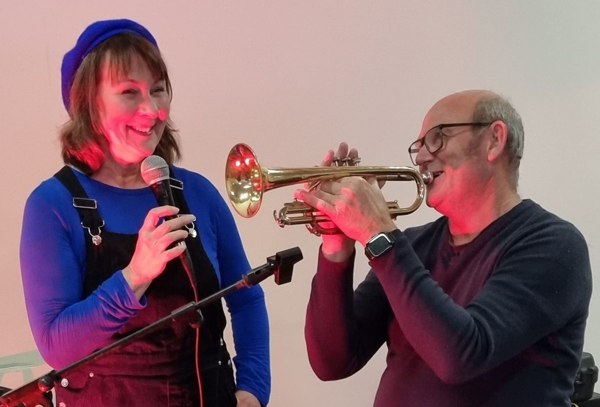 A woman holding a microphone and a man playing a trumpet