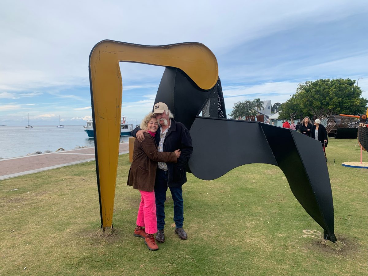 Woman and man hugging in front of sculpture 