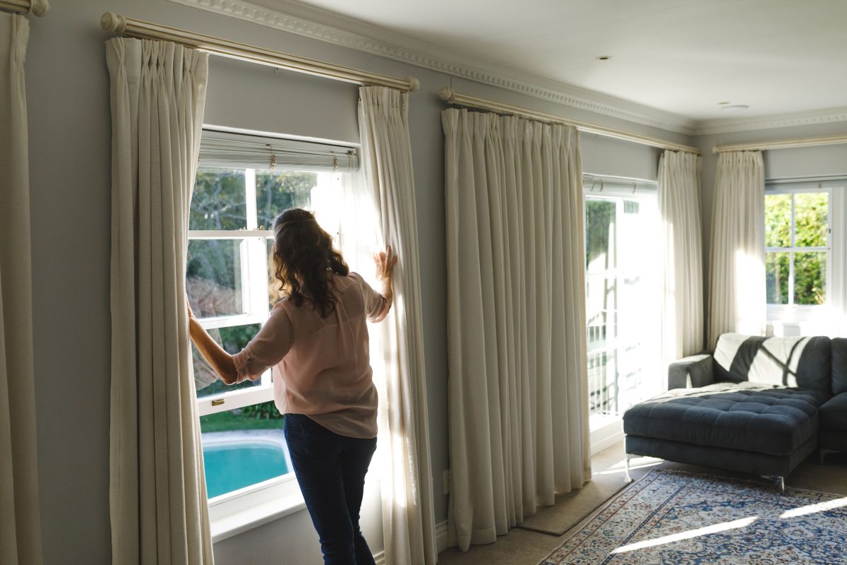 woman opening curtains