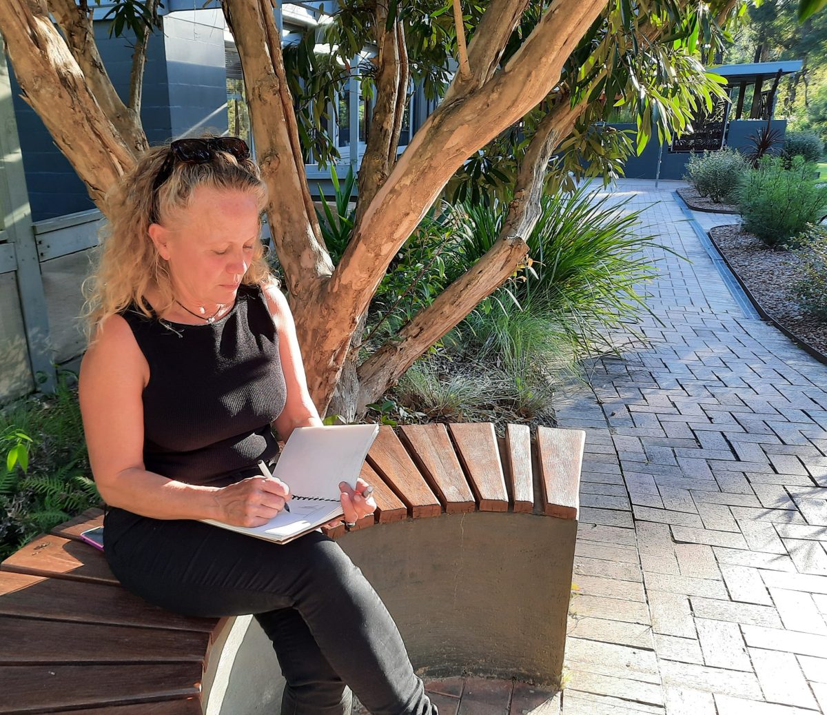 A woman sitting outside and writing in a journal